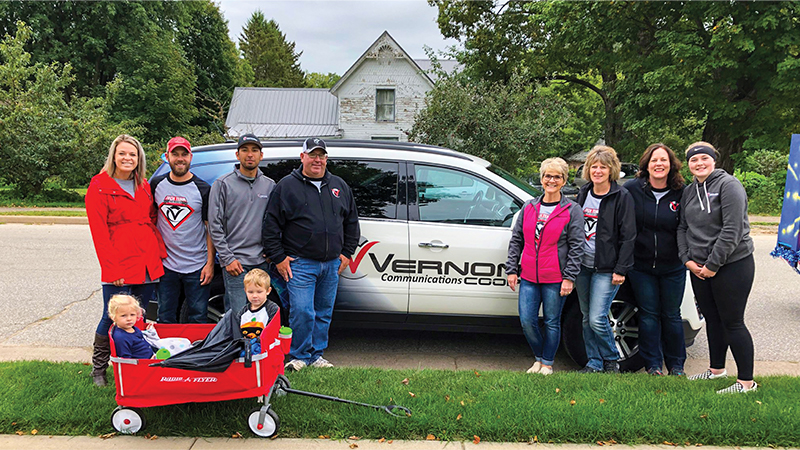 Vernon Communications Team together in front of the company car